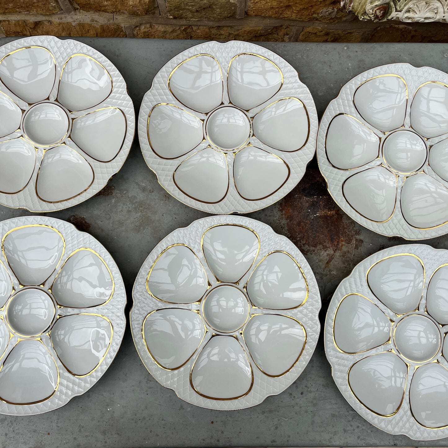 French oyster plates in white porcelain featuring elegant gold detailing along the edges. The plates have a classic, vintage design with subtle scalloped rims, reflecting refined French tableware style.