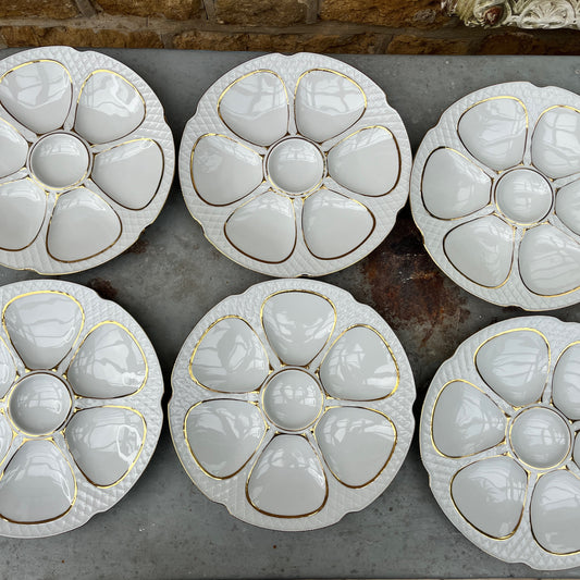 French oyster plates in white porcelain featuring elegant gold detailing along the edges. The plates have a classic, vintage design with subtle scalloped rims, reflecting refined French tableware style.