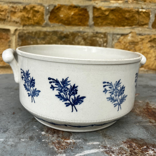 A vintage French provincial white earthenware bowl decorated with traditional cobalt blue floral motifs. The bowl features a gently rounded form and aged glazed finish, giving it a charming rustic character.