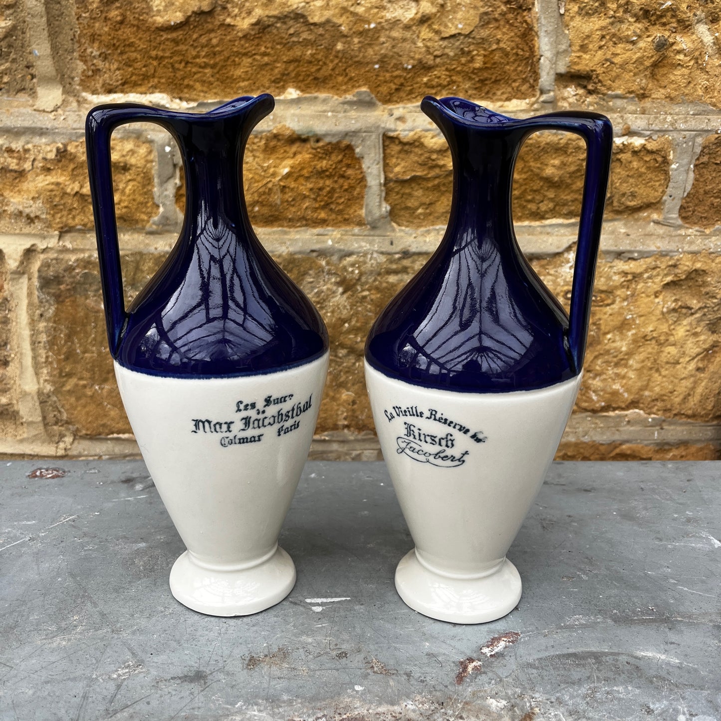Two blue and white ceramic vases with text on a stone surface 