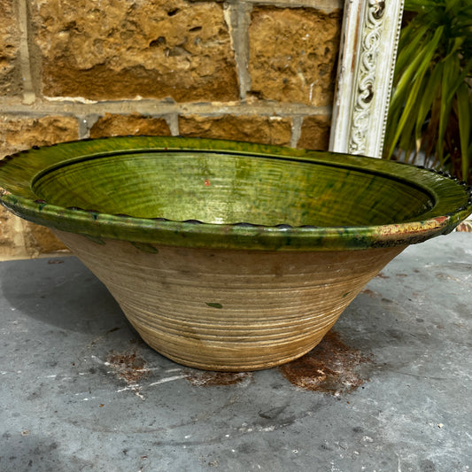 An 18th-century Tian bowl in glazed green earthenware with a simple, hand-crafted form and richly aged finish. The bowl features a wide, gently flared rim and a deep rounded shape, showcasing subtle variations in the green glaze that reflect its age and traditional craftsmanship