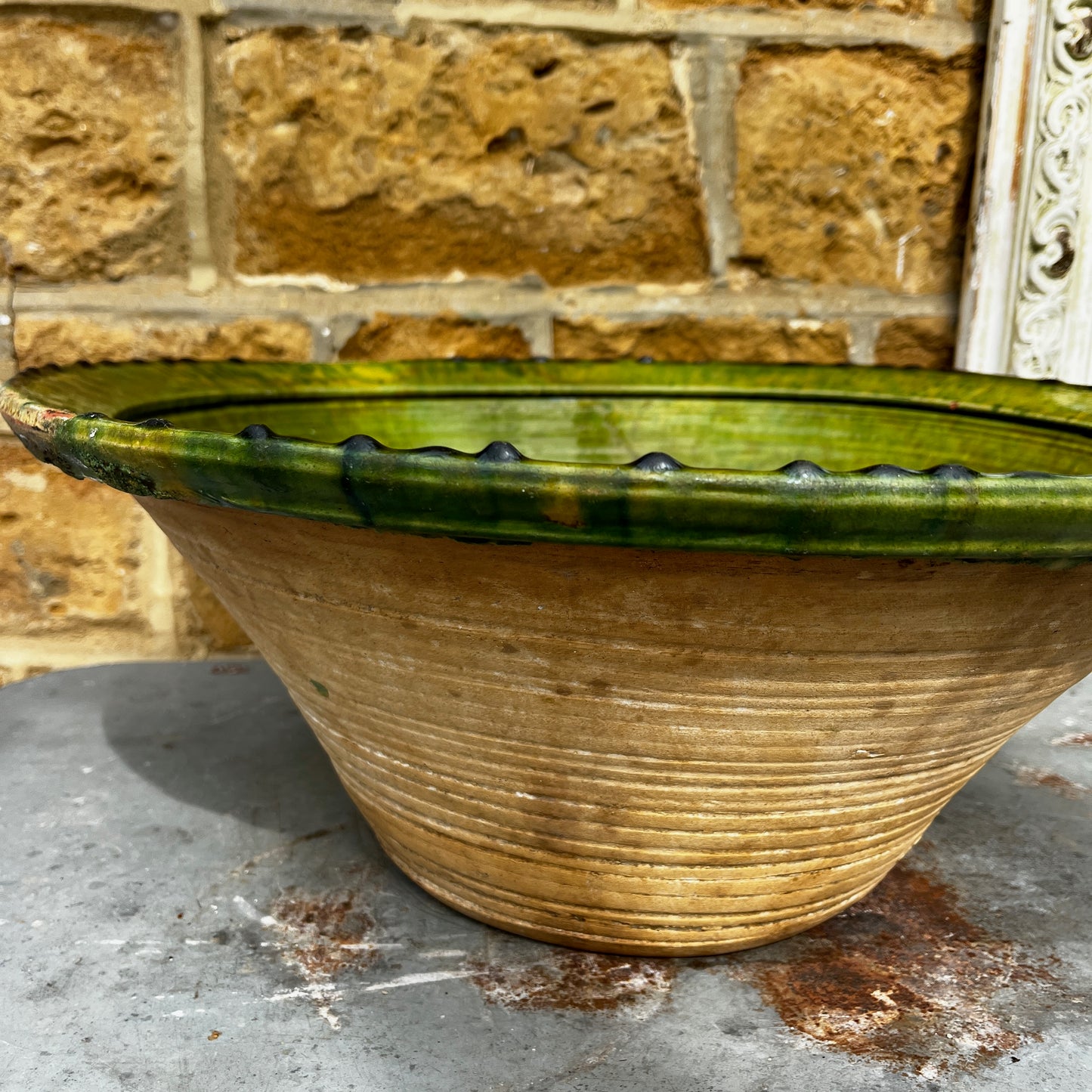 An 18th-century Tian bowl in glazed green earthenware with a simple, hand-crafted form and richly aged finish. The bowl features a wide, gently flared rim and a deep rounded shape, showcasing subtle variations in the green glaze that reflect its age and traditional craftsmanship