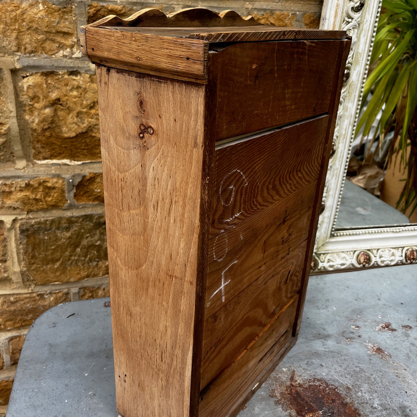 Vintage French wall cupboard with a mirrored door and a single drawer beneath. The interior of the cupboard and the base of the drawer are lined with decorative French paper, adding character and charm to the aged wooden piece.