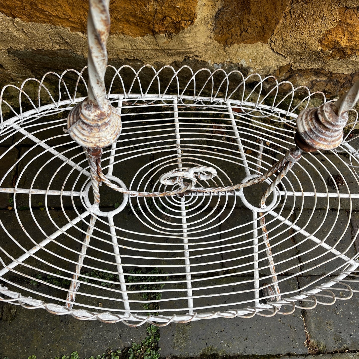 Two tier white vintage wire plant stand with two oval wire shelves with decorative scalloped edging.