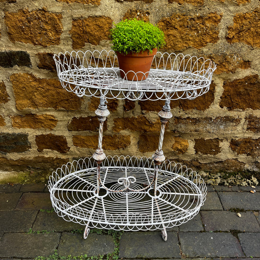 Two tier white vintage wire plant stand with two oval wire shelves with decorative scalloped edging.