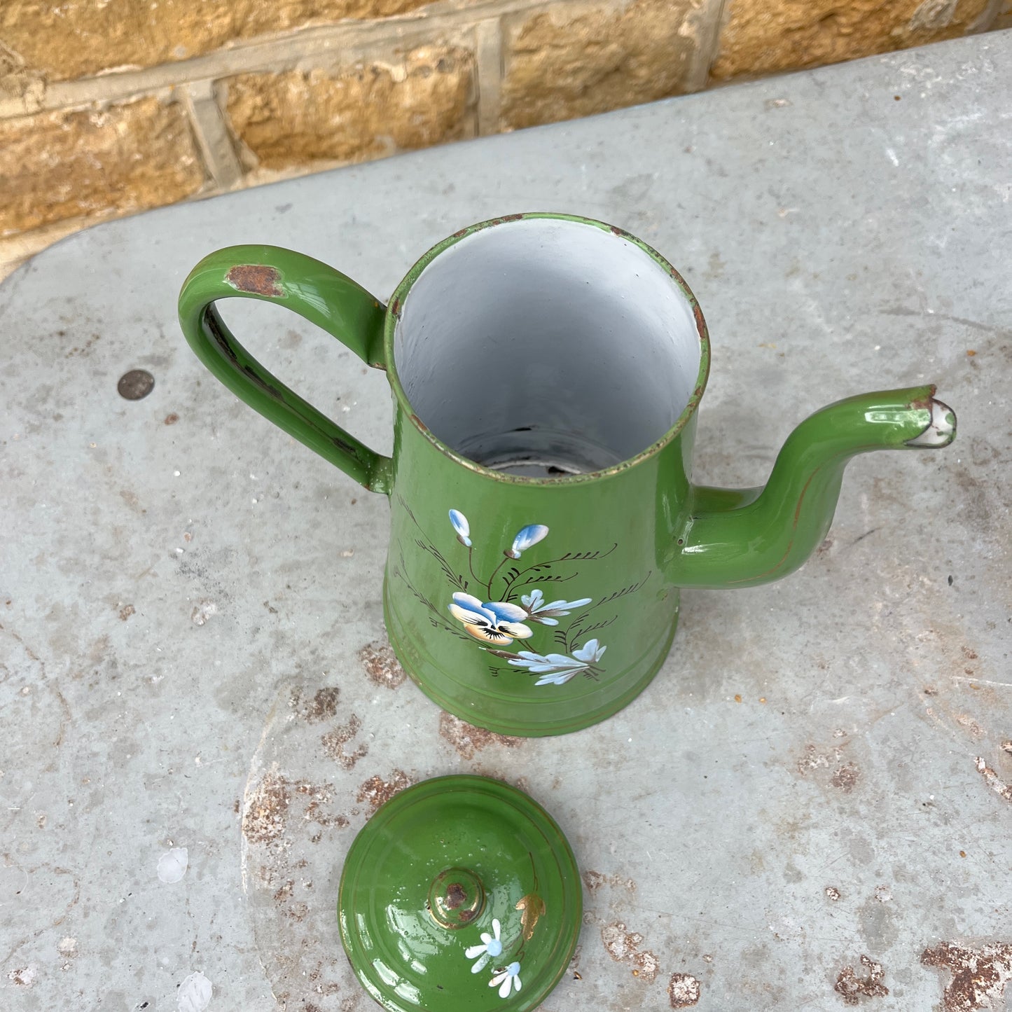 Vintage green enamel coffee pot with hand-painted floral decoration and a separate lid. The pot shows subtle signs of age and wear, highlighting its charming, rustic, and antique kitchen style