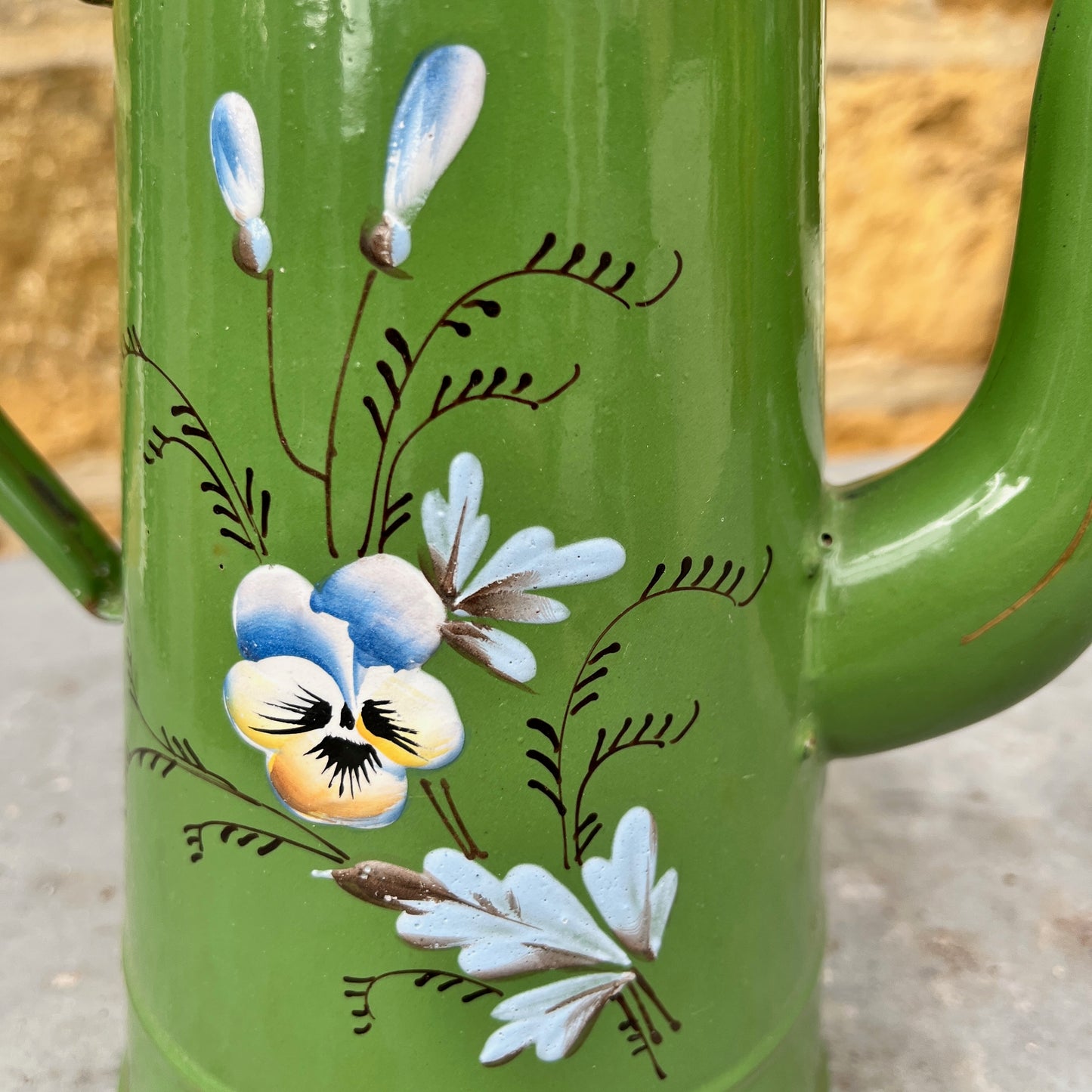 Vintage green enamel coffee pot with hand-painted floral decoration and a separate lid. The pot shows subtle signs of age and wear, highlighting its charming, rustic, and antique kitchen style