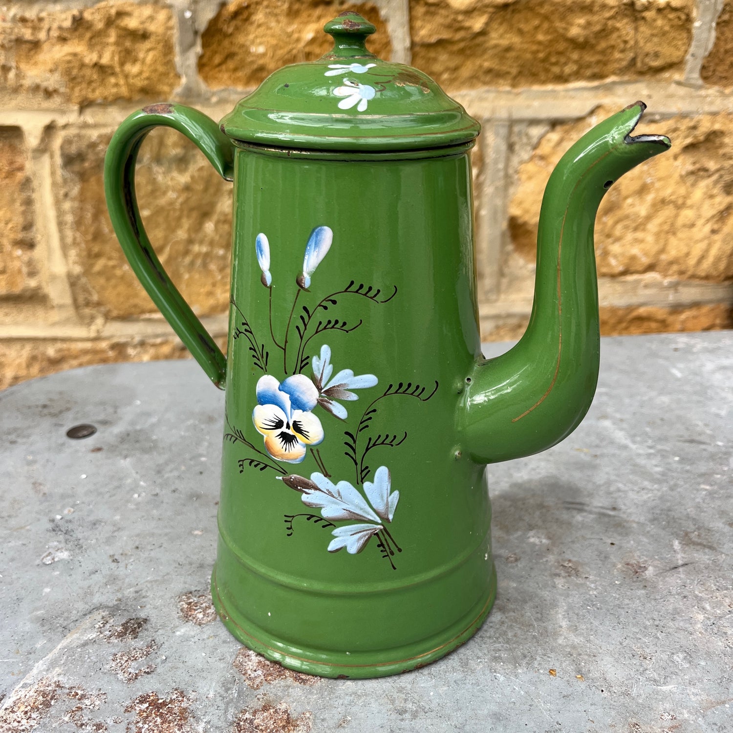 Vintage green enamel coffee pot with hand-painted floral decoration and a hinged lid. The pot shows subtle signs of age and wear, highlighting its charming, rustic, and antique kitchen style