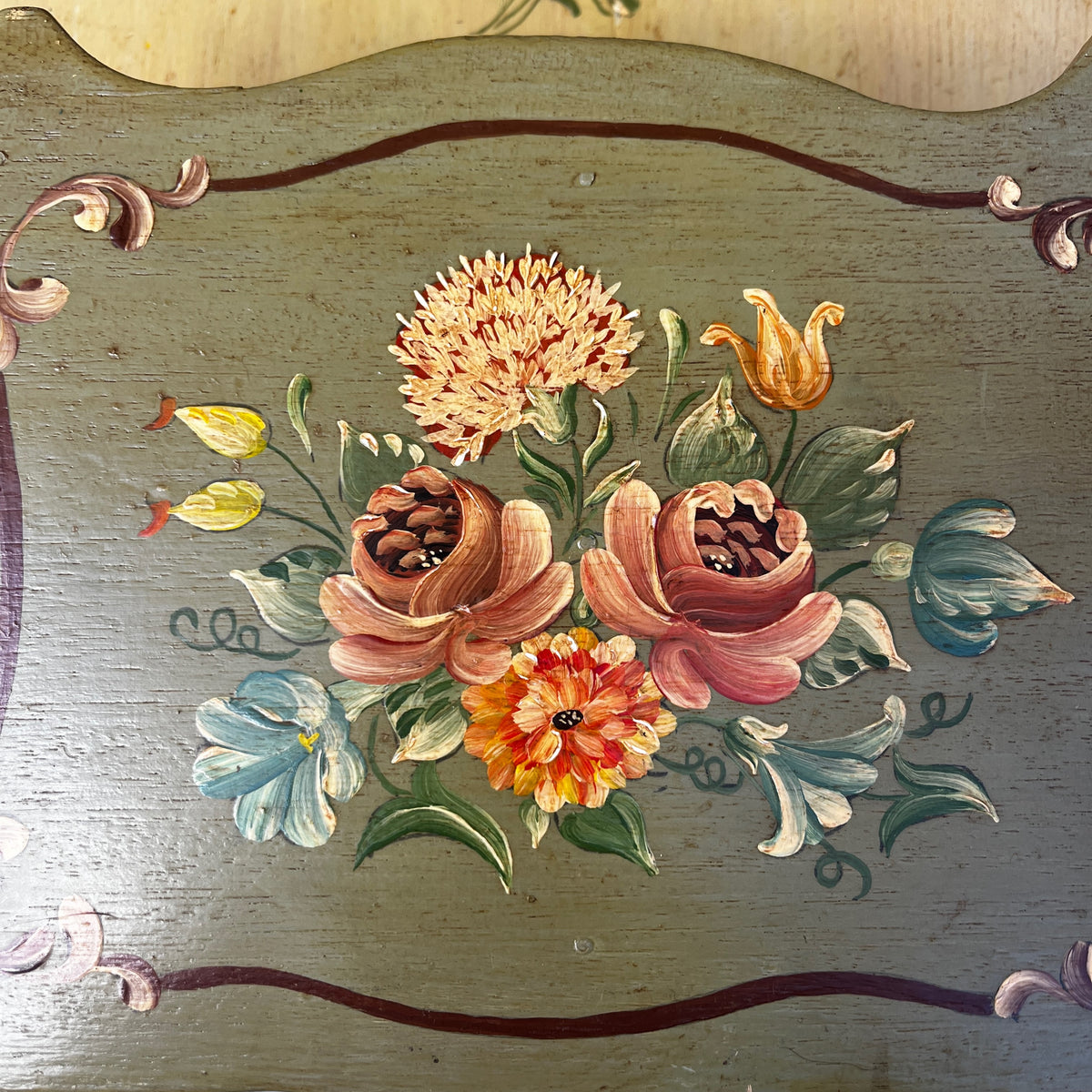 A vintage hand-painted wooden wall letter rack with a two-tone design, featuring a light natural wood top section and a muted sage green bottom section, both decorated with colorful floral motifs. 