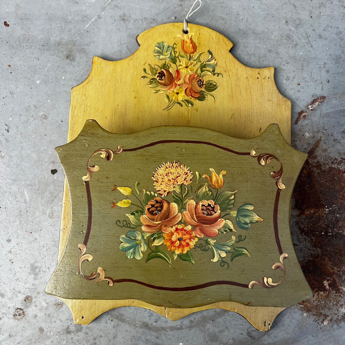 A vintage hand-painted wooden wall letter rack with a two-tone design, featuring a light natural wood top section and a muted sage green bottom section, both decorated with colorful floral motifs. 