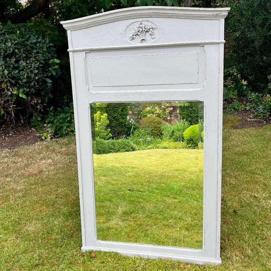A grey French-style mirror from the 1920s/30s, featuring a bevelled glass edge and an ornate wooden frame with subtle carvings and a distressed finish. The rectangular mirror exudes elegant vintage charm