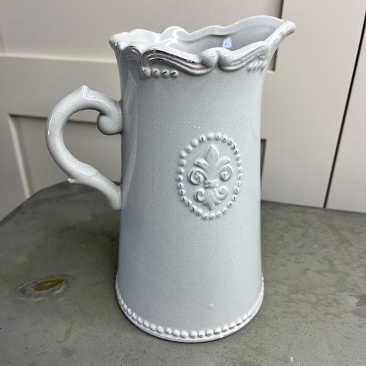 Decorative gray pitcher with intricate designs on a surface.