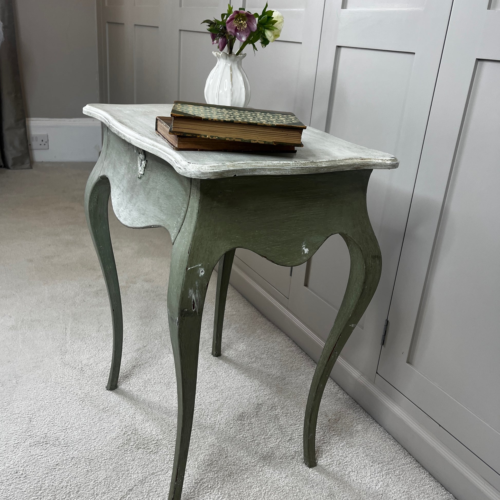 
Gustavian-style bedside table with a single drawer, painted green with a contrasting off-white top, featuring simple classical lines and a softly distressed vintage finish.
