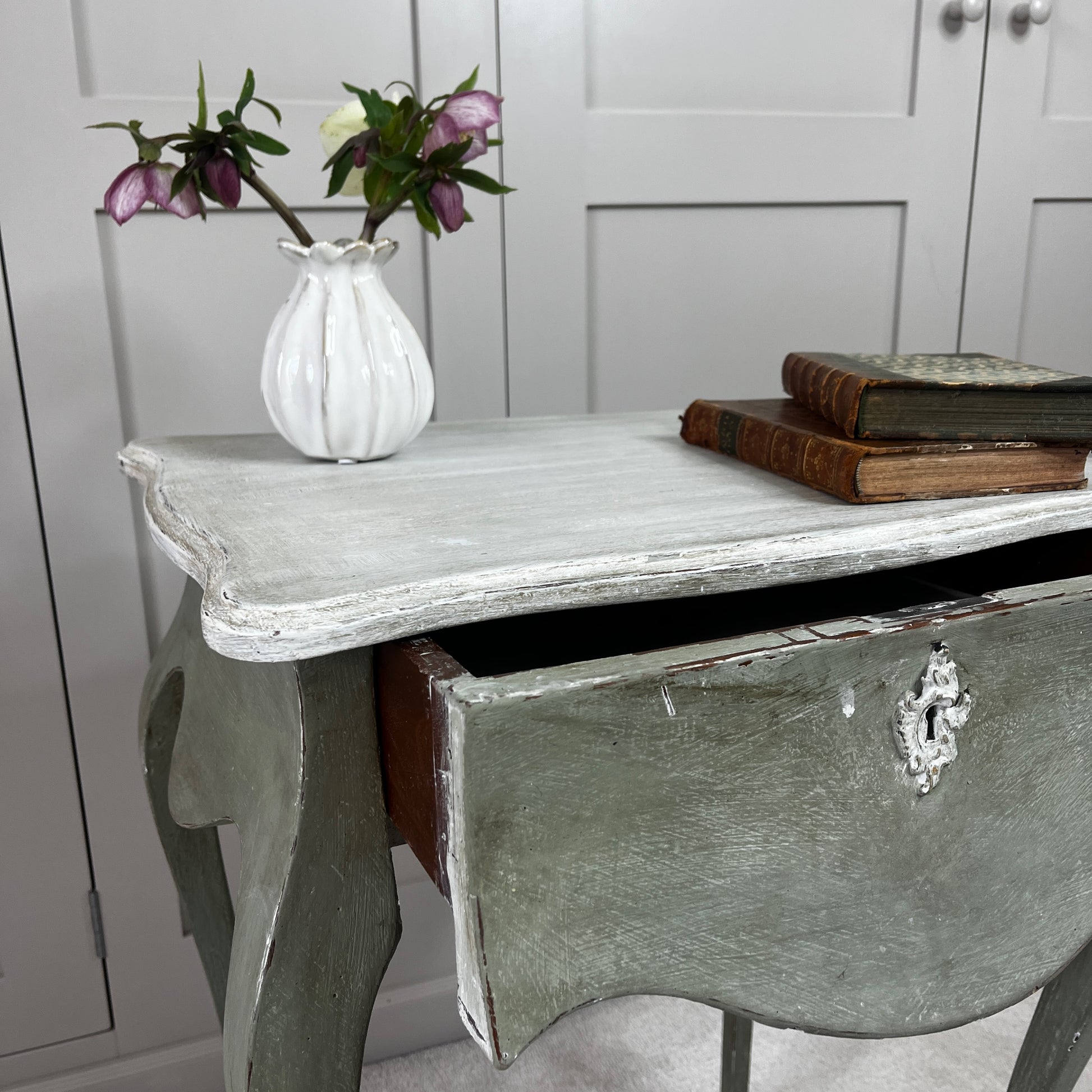
Gustavian-style bedside table with a single drawer, painted green with a contrasting off-white top, featuring simple classical lines and a softly distressed vintage finish.
