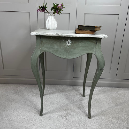 
Gustavian-style bedside table with a single drawer, painted green with a contrasting off-white top, featuring simple classical lines and a softly distressed vintage finish.
