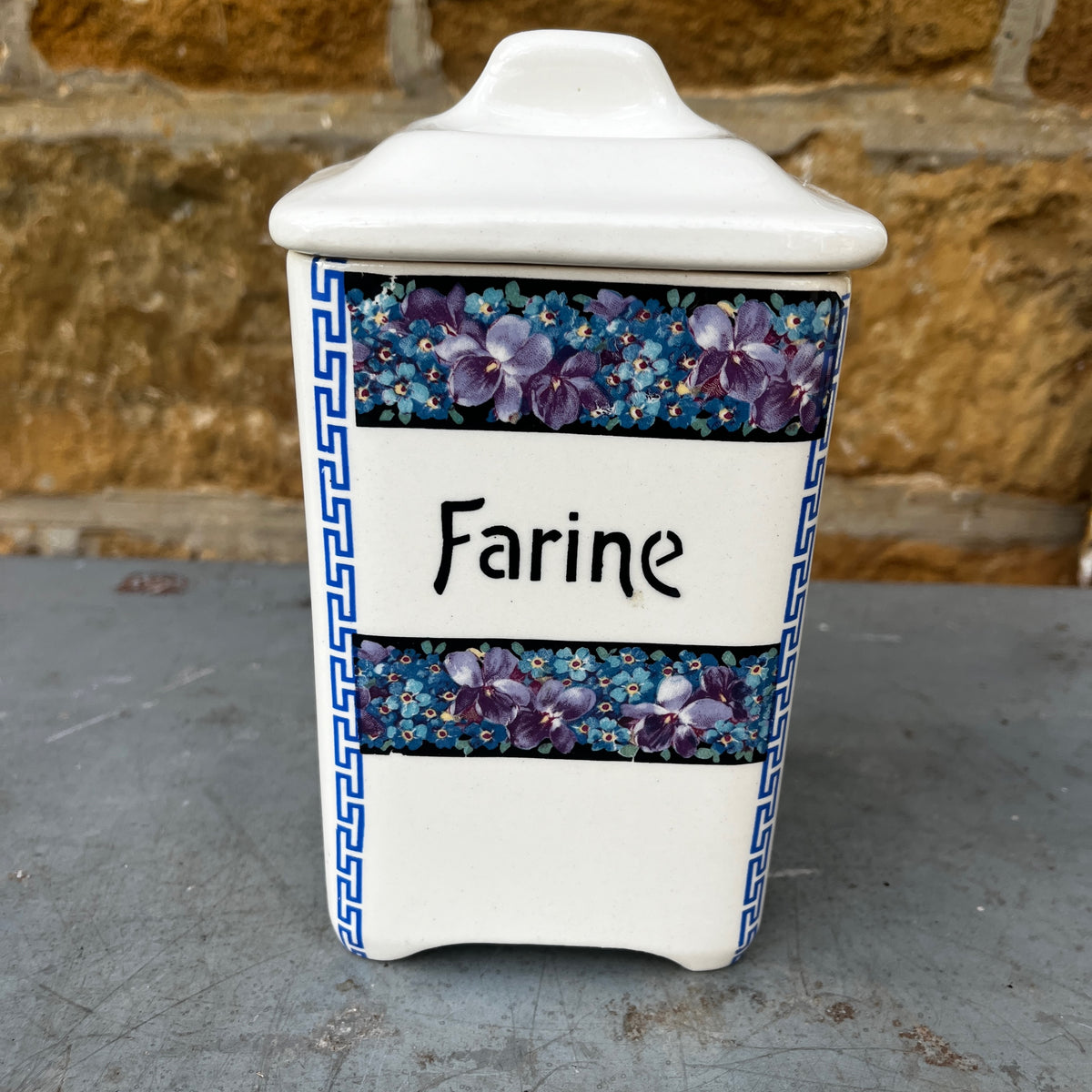 Five ceramic kitchen canisters arranged together, each decorated with a floral transfer print and French lettering on a vintage Czechoslovakian design