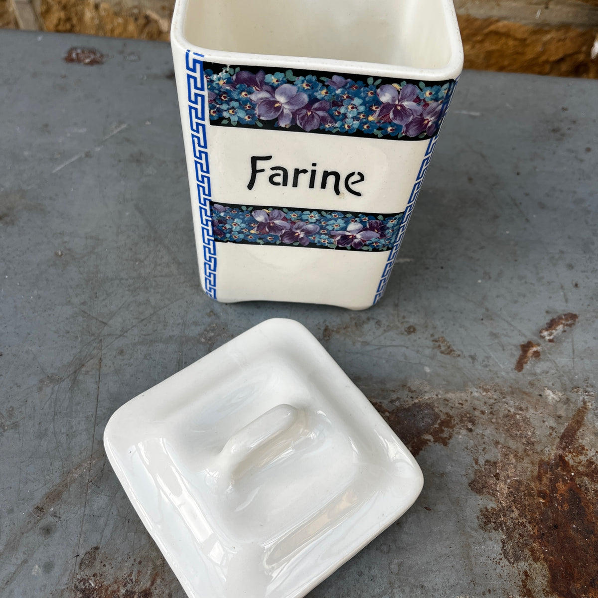 Five ceramic kitchen canisters arranged together, each decorated with a floral transfer print and French lettering on a vintage Czechoslovakian design