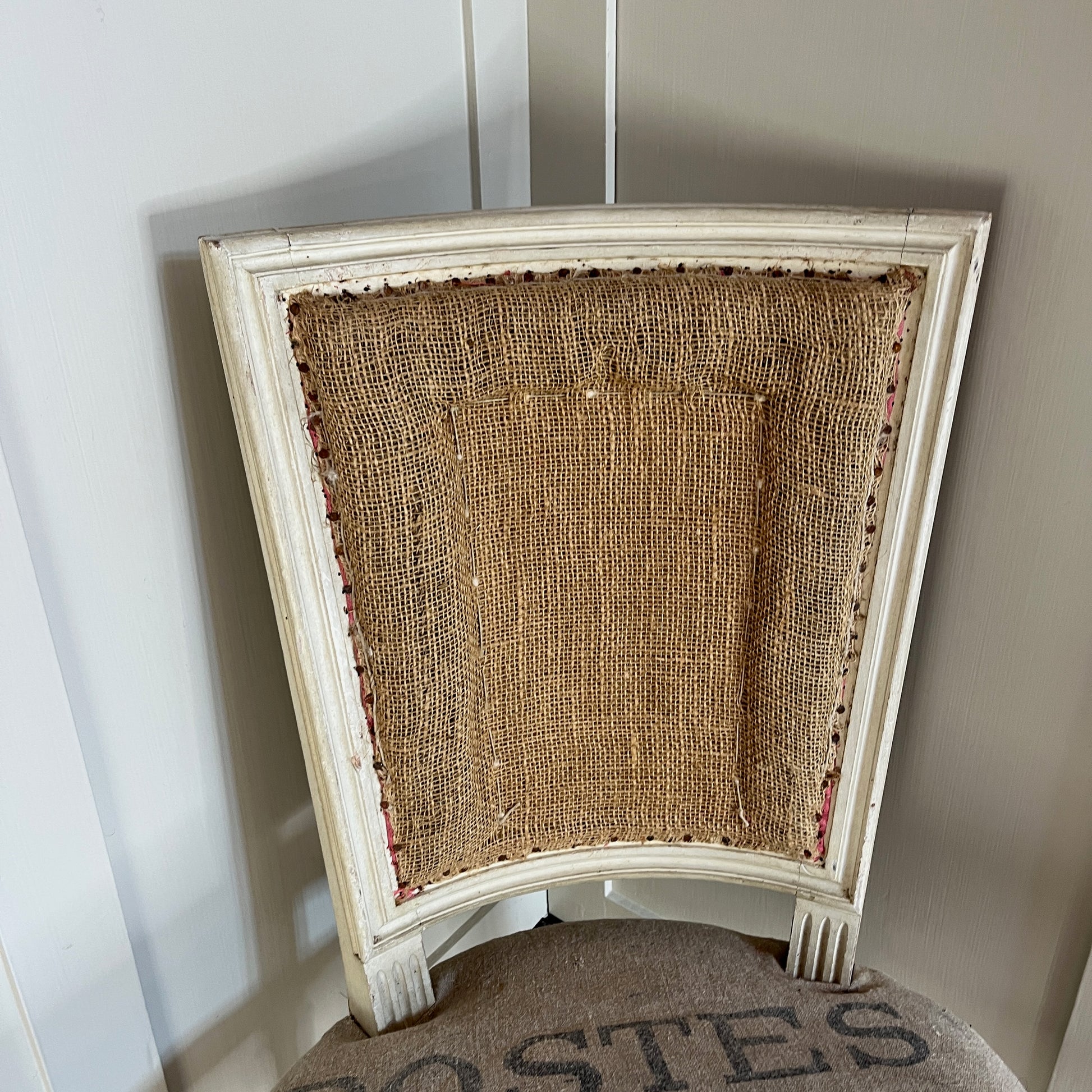 A French chair with a semi-upholstered design, featuring a wooden frame painted in a distressed finish and a back & seat covered in La Poste fabric with its iconic grey and black postal pattern. The chair combines rustic elegance with vintage charm