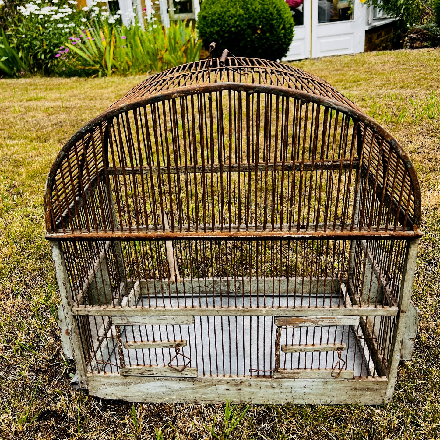 Large vintage birdcage with an ornate metal frame, featuring a domed top, decorative detailing, and a weathered aged finish.