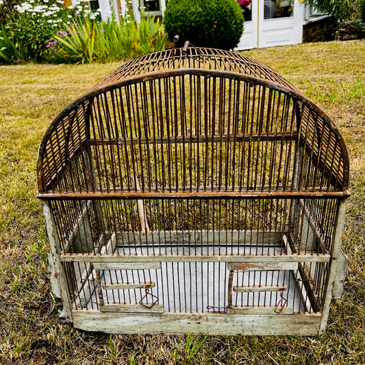 Large vintage birdcage with an ornate metal frame, featuring a domed top, decorative detailing, and a weathered aged finish.