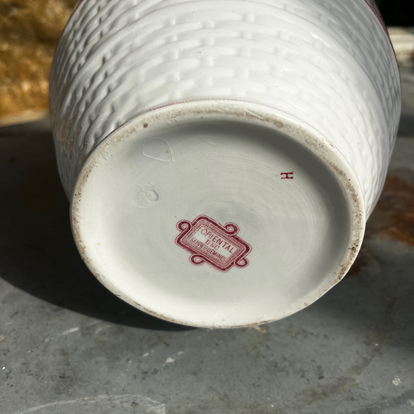 An antique French Sarreguemines ironstone pitcher featuring a classic pink transferware floral pattern on a creamy white background. The generously sized pitcher has a curved handle, gently flared rim, and elegant rounded form, with subtle signs of age and wear that enhance its vintage character.