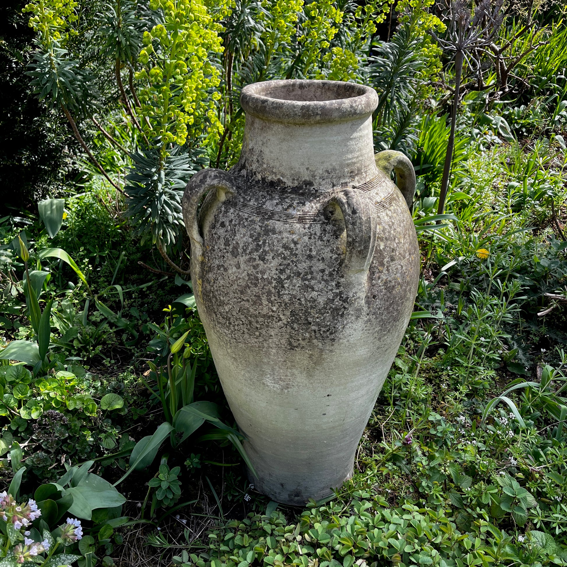 Large rustic garden urn with an aged weathered surface and traces of green lichen, featuring a classic decorative shape and timeworn outdoor character.