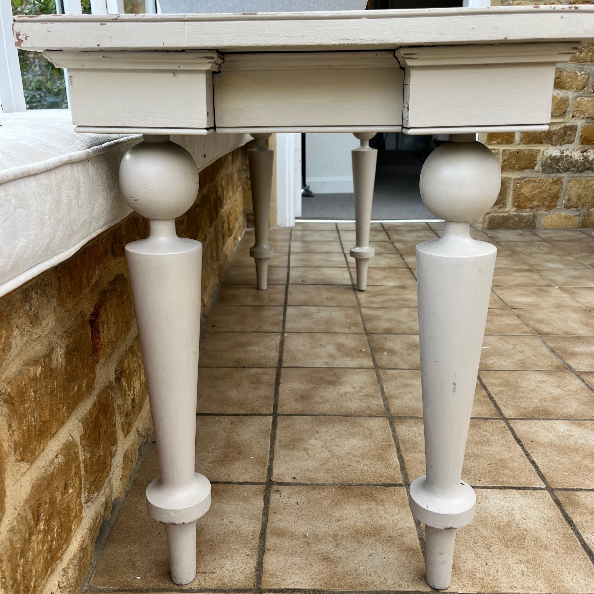 A long grey vintage console table with a weathered finish, featuring a sleek rectangular top and small drawers at each end. The table stands on decorative legs, exuding elegance