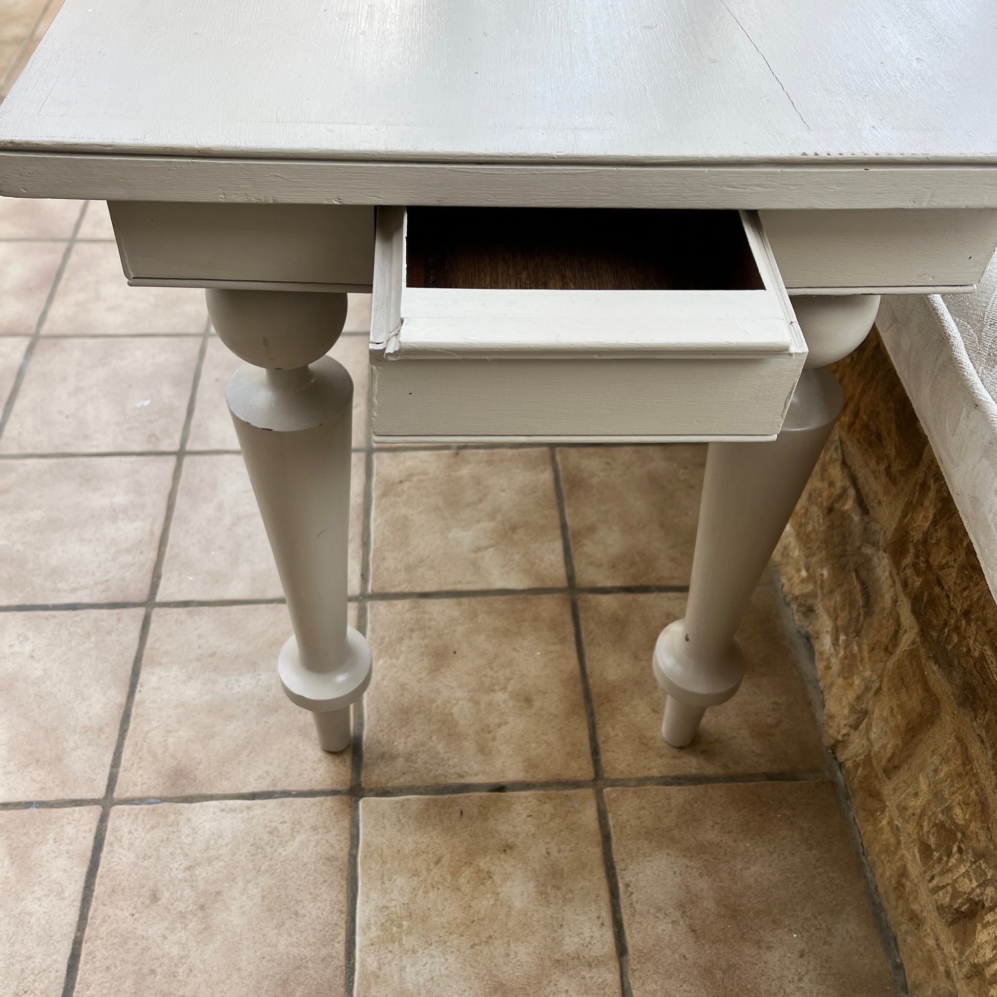 A long grey vintage console table with a weathered finish, featuring a sleek rectangular top and small drawers at each end. The table stands on decorative legs, exuding elegance