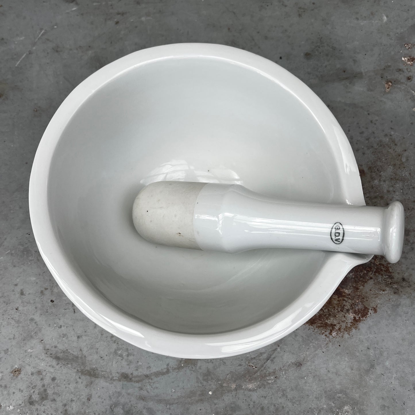 A large vintage GDV porcelain pestle and mortar with a classic white glazed finish and substantial, heavy design. The deep bowl features a pouring lip and sturdy rounded base, accompanied by a matching porcelain pestle
