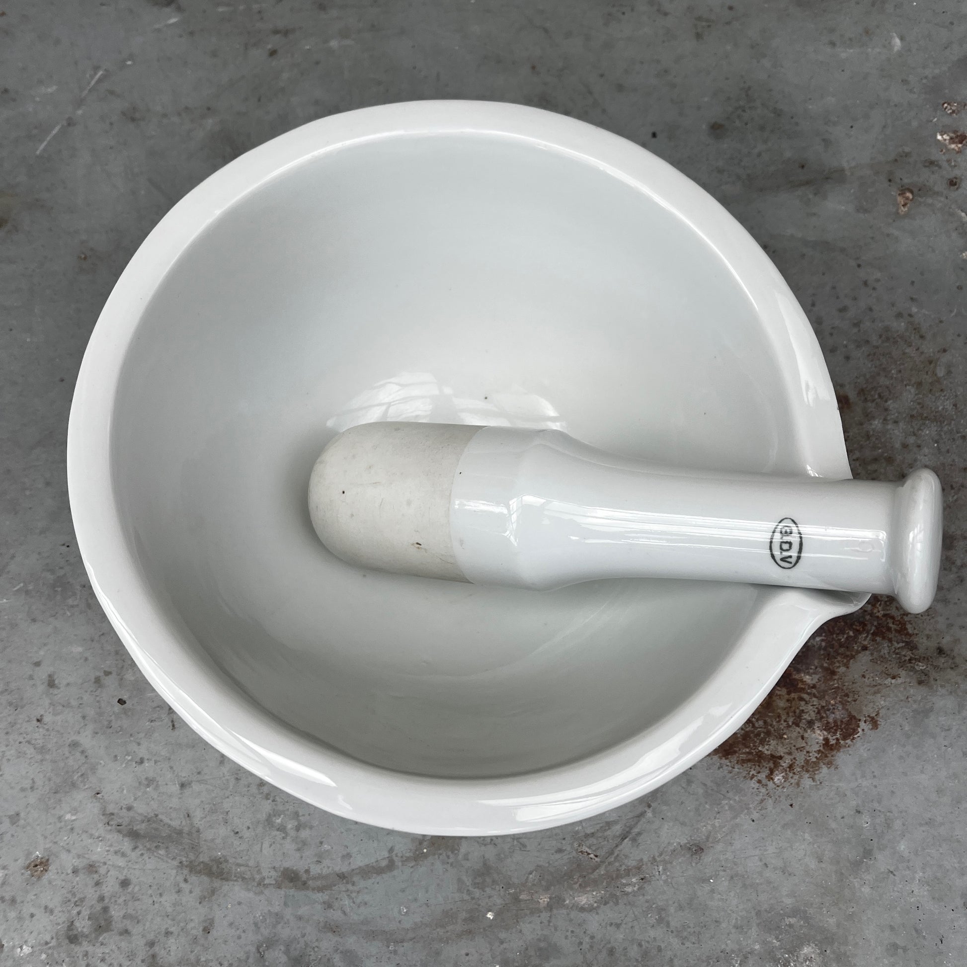 A large vintage GDV porcelain pestle and mortar with a classic white glazed finish and substantial, heavy design. The deep bowl features a pouring lip and sturdy rounded base, accompanied by a matching porcelain pestle