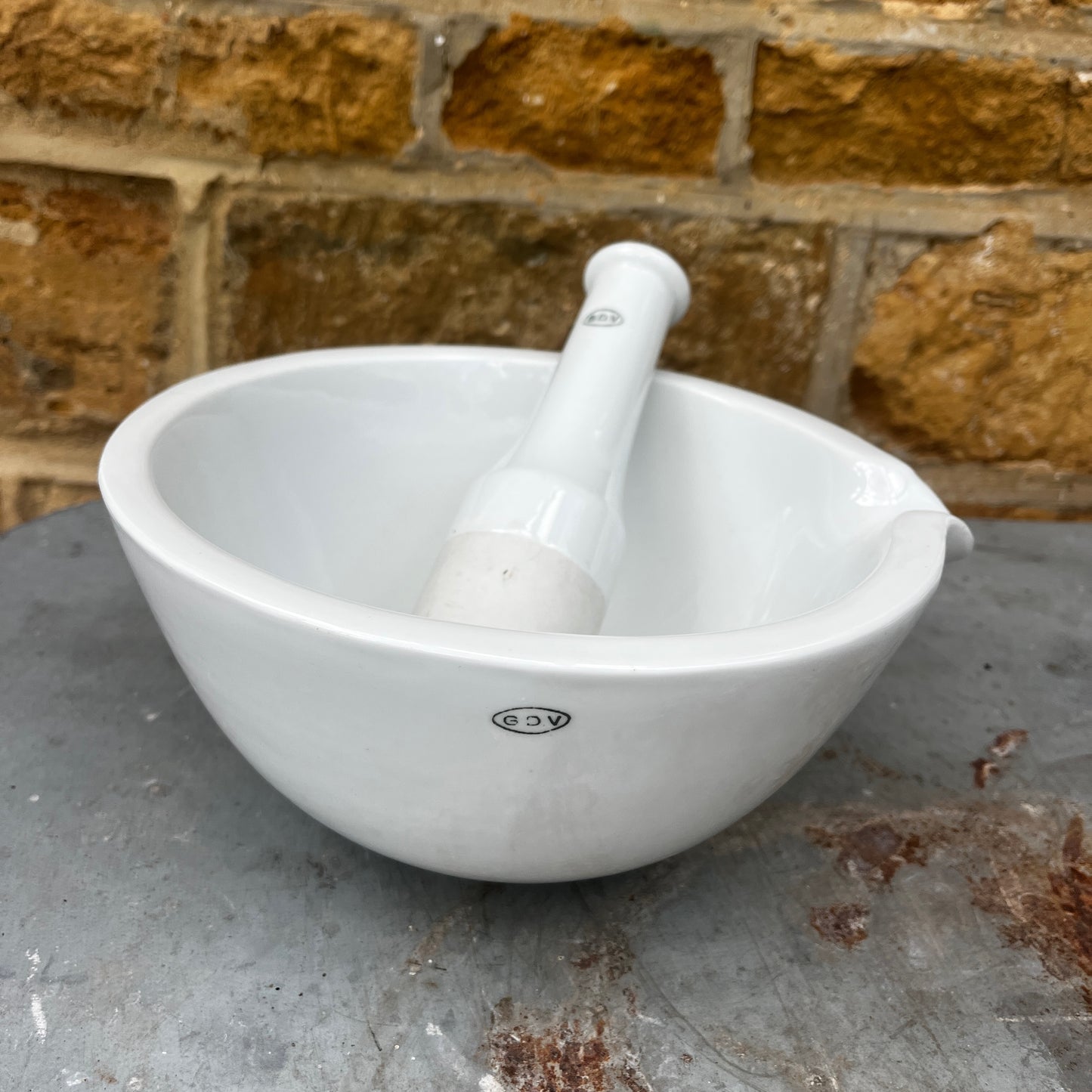 A large vintage GDV porcelain pestle and mortar with a classic white glazed finish and substantial, heavy design. The deep bowl features a pouring lip and sturdy rounded base, accompanied by a matching porcelain pestle