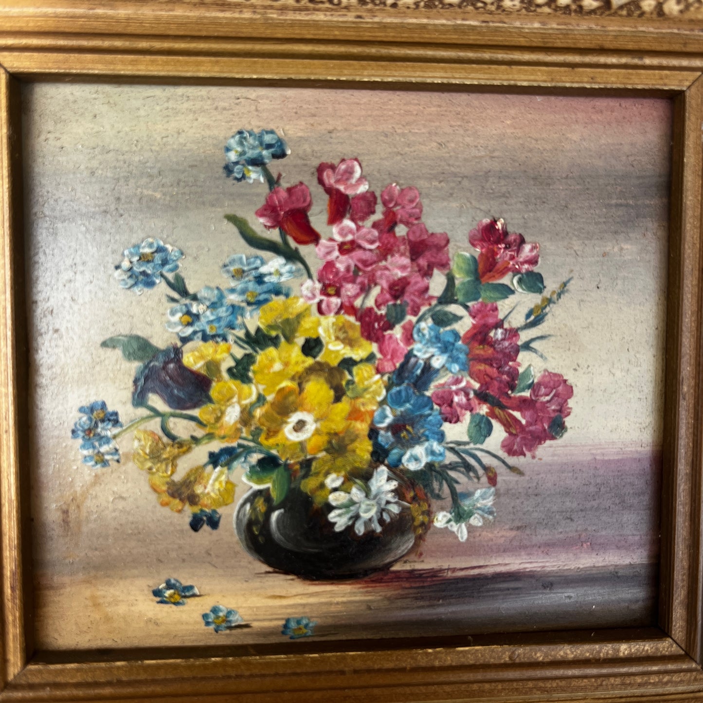 A framed vintage oil painting on canvas depicting a traditional floral still life, with an arrangement of flowers in a decorative vase.  In a decorative frame.
