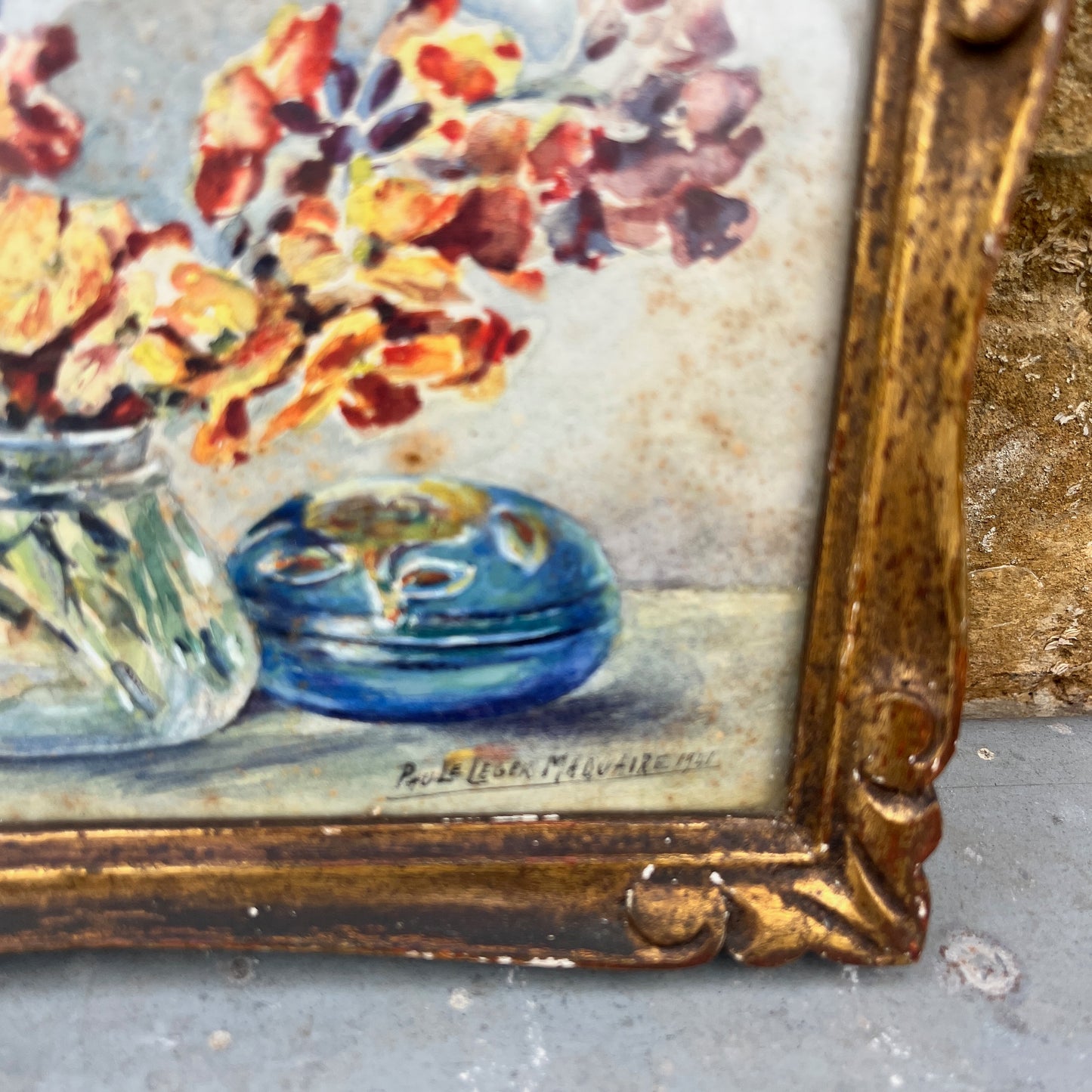 Vintage painting of flowers and a blue pot in a gold frame.