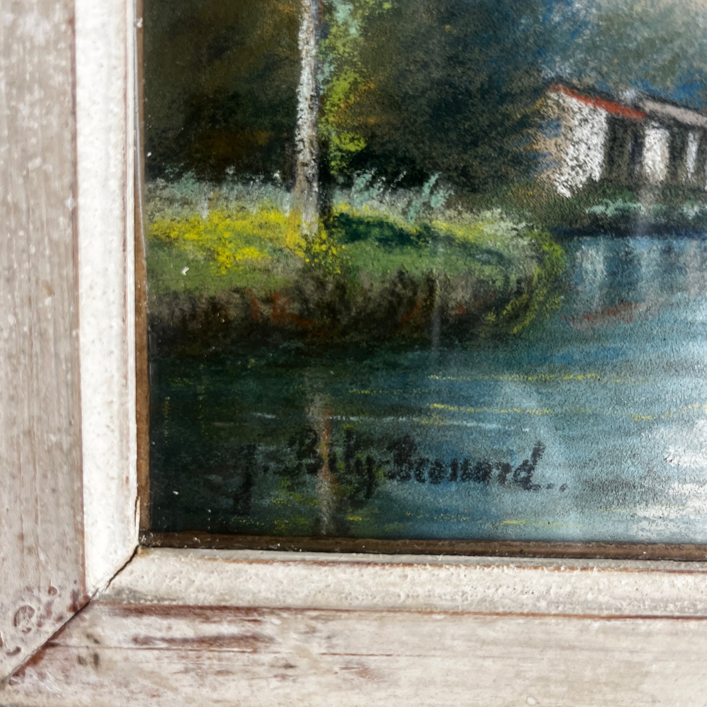A vintage oil painting of a tranquil wooded landscape featuring a calm river or lake reflecting the sky, with trees lining the water and a small building nestled among the trees in the distance.  Montparnasse Frame.