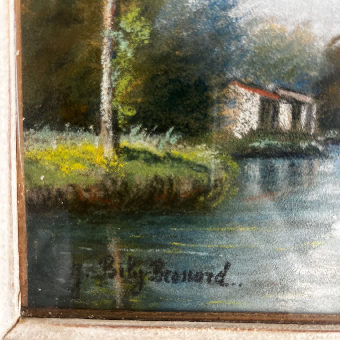 A vintage oil painting of a tranquil wooded landscape featuring a calm river or lake reflecting the sky, with trees lining the water and a small building nestled among the trees in the distance.  Montparnasse Frame.