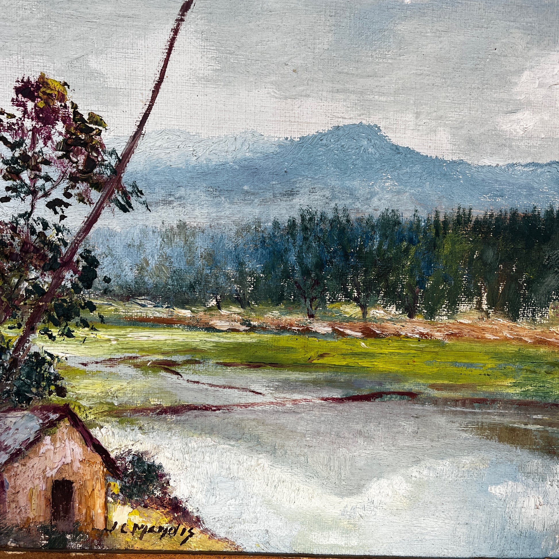 Framed vintage oil on board painting of a mountain lake scene, depicting tranquil water surrounded by rugged peaks and soft atmospheric light.