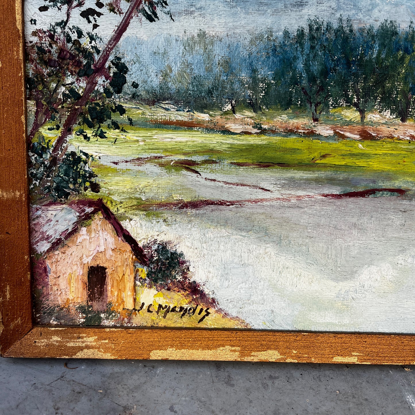 Framed vintage oil on board painting of a mountain lake scene, depicting tranquil water surrounded by rugged peaks and soft atmospheric light.