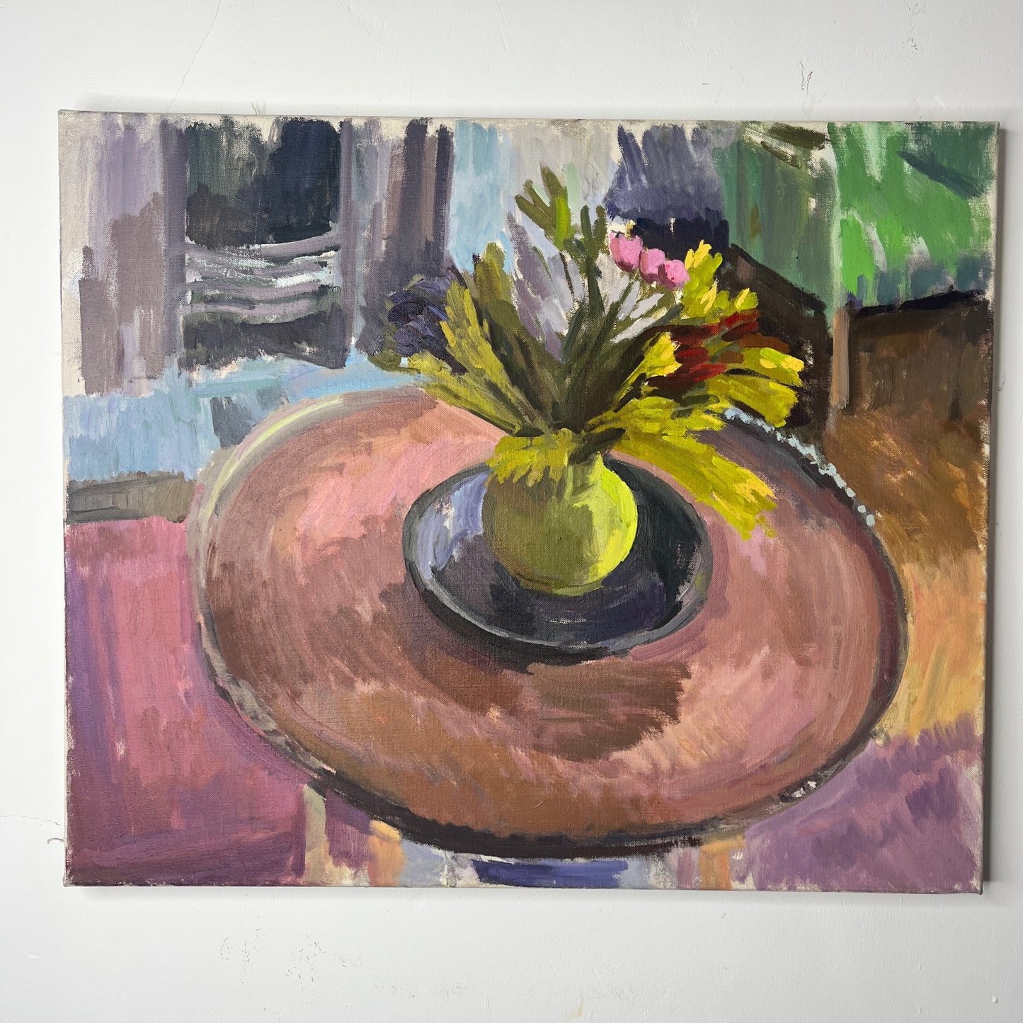 An oil-on-canvas still life painting capturing a serene living room scene, featuring a bouquet of pink tulips gracefully arranged in a green vase on a wooden table. In the room is a green armchair, and fire place, evoking a sense of quiet elegance. and coziness.