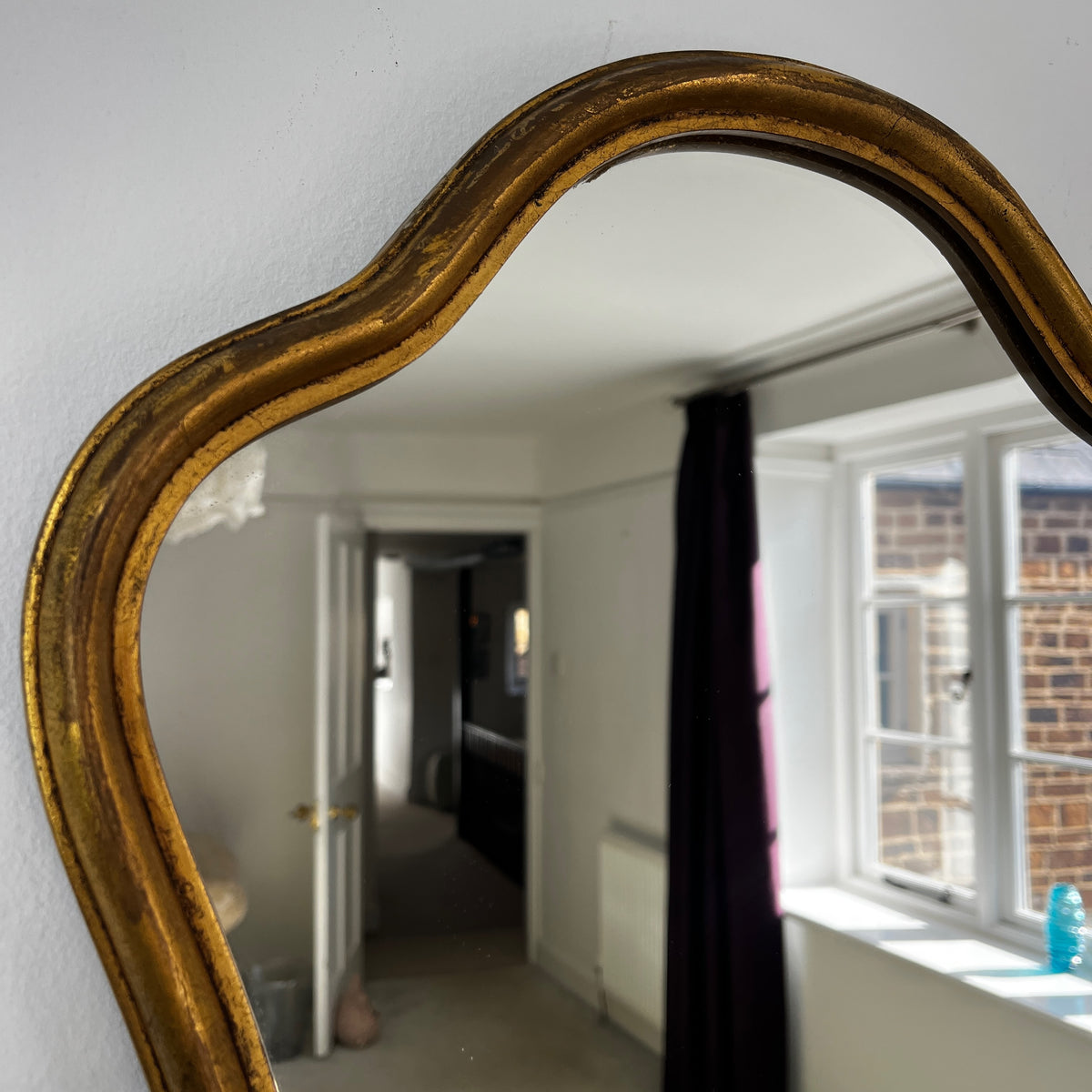 Vintage French Rococo-style wall mirror with an ornate giltwood frame and decorative carved detailing