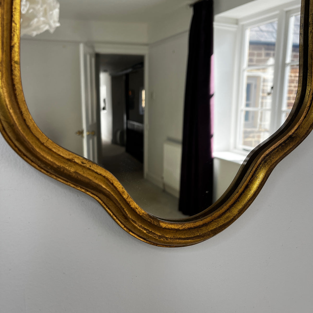 Vintage French Rococo-style wall mirror with an ornate giltwood frame and decorative carved detailing