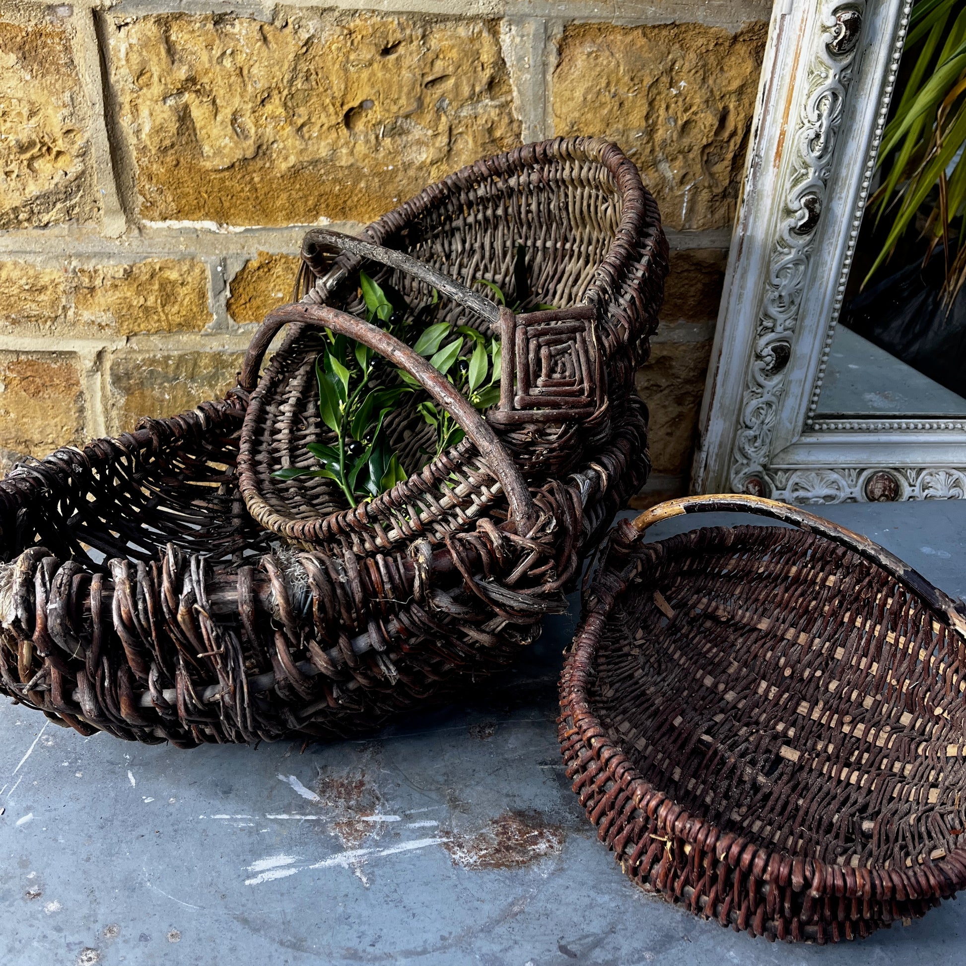 Rustic French wicker baskets with hand-woven construction and a natural, weathered finish. The baskets feature sturdy handles and textured surfaces, reflecting traditional French country craftsmanship.