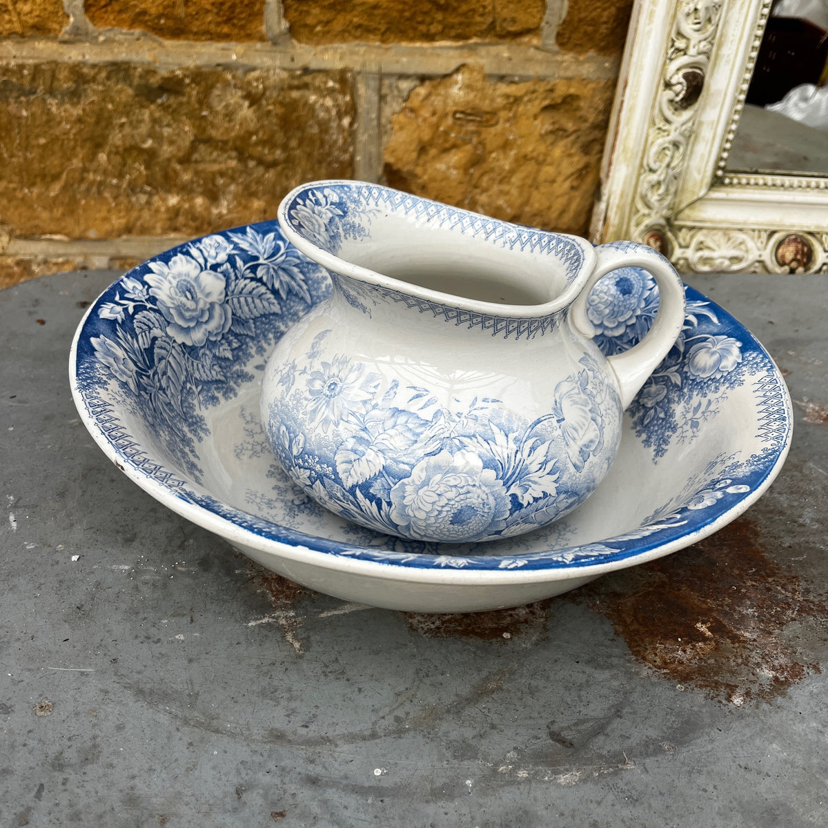 A blue and white ceramic pitcher with a floral pattern, placed inside a matching deep bowl.