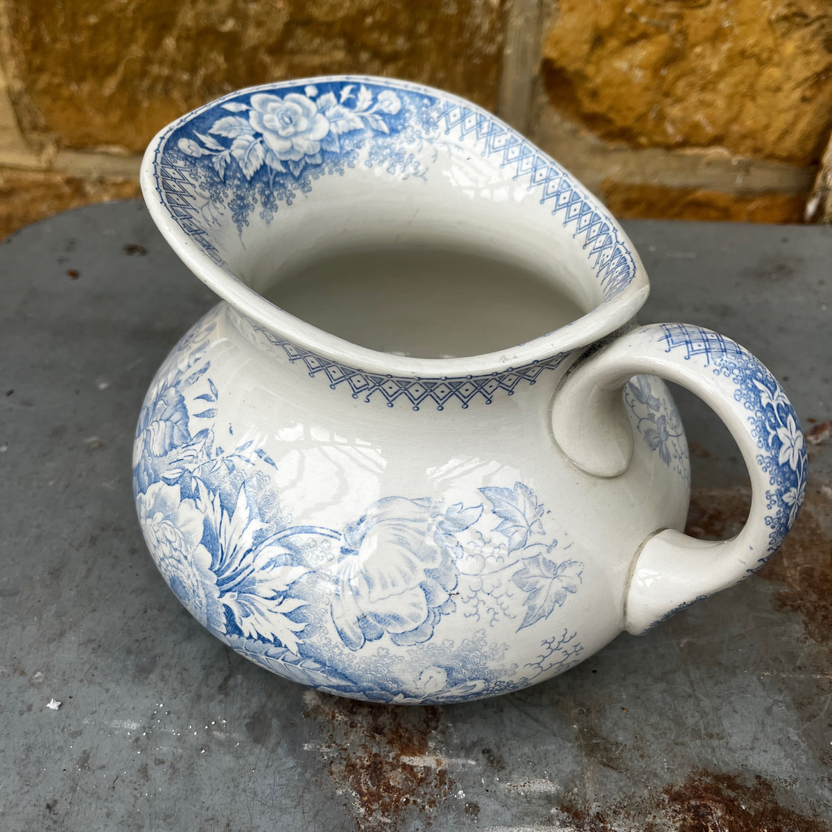 A blue and white ceramic pitcher with a floral pattern, placed inside a matching deep bowl.