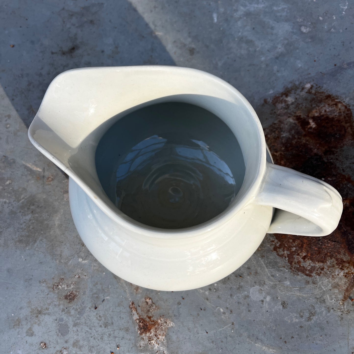 Simple French white ceramic jug with a rounded body, curved handle, and minimalist glazed finish in a classic utilitarian style.
