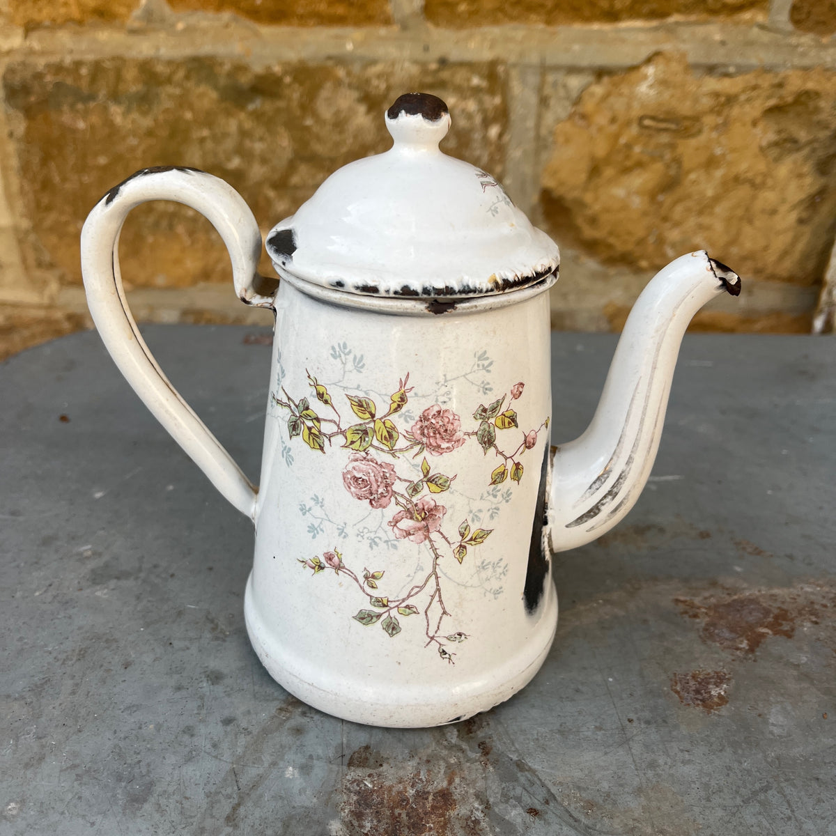 A vintage white enamel coffee pot with a floral rose pattern