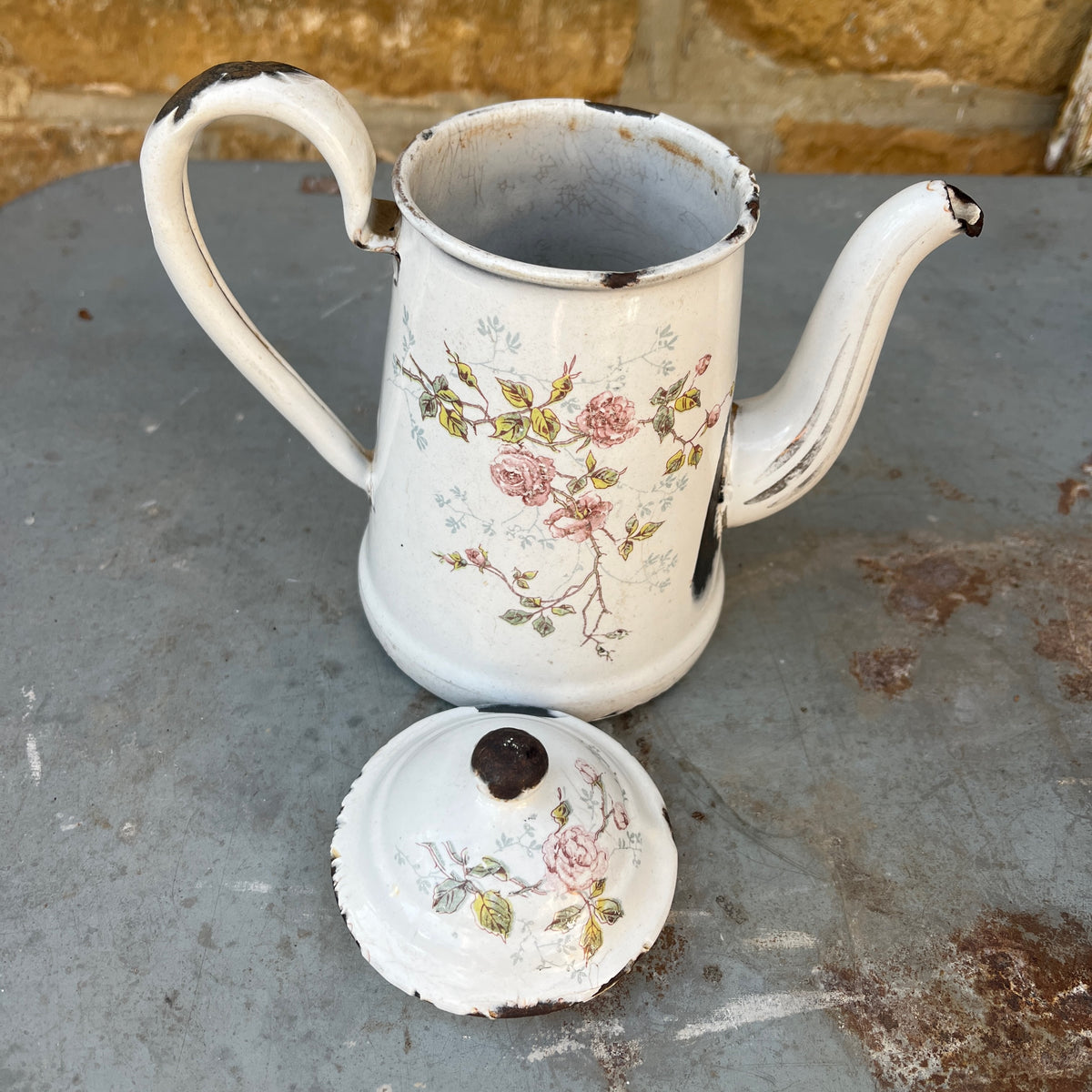 A vintage white enamel coffee pot with a floral rose pattern