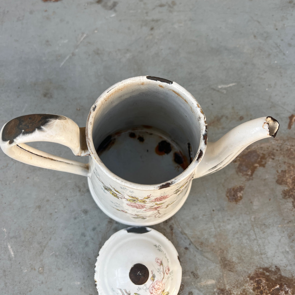 A vintage white enamel coffee pot with a floral rose pattern
