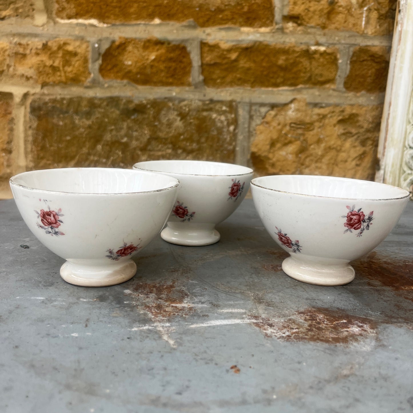 A small vintage French ceramic bowl with a delicate rose decoration in soft pink and green tones