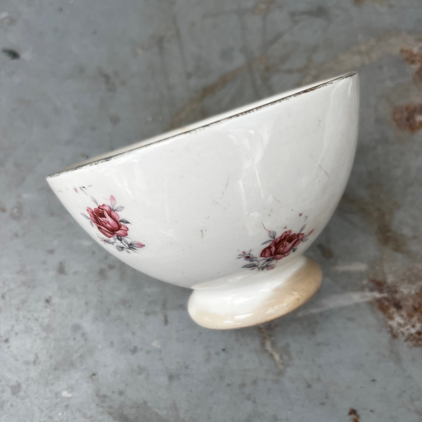 A small vintage French ceramic bowl with a delicate rose decoration in soft pink and green tones