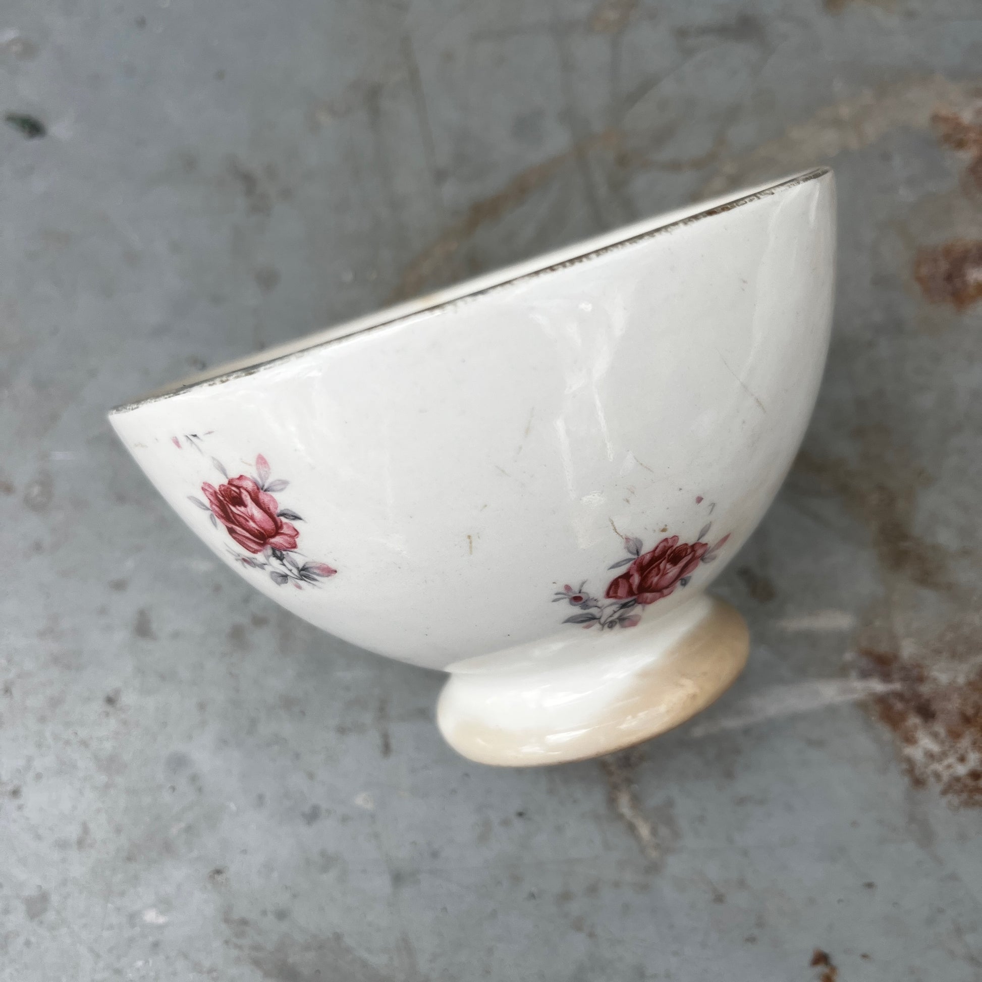 A small vintage French ceramic bowl with a delicate rose decoration in soft pink and green tones
